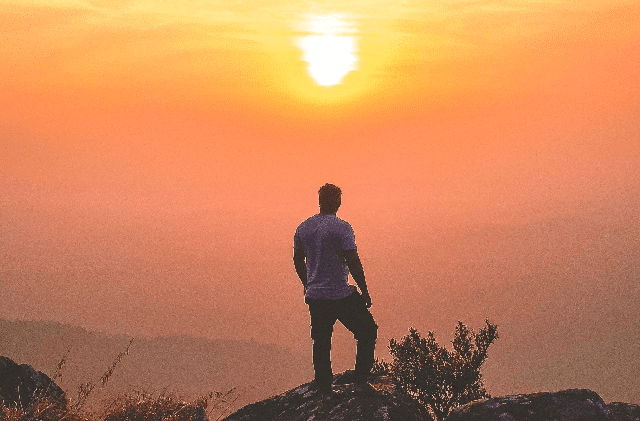 Man Standing on top of mountain looking to horizon
